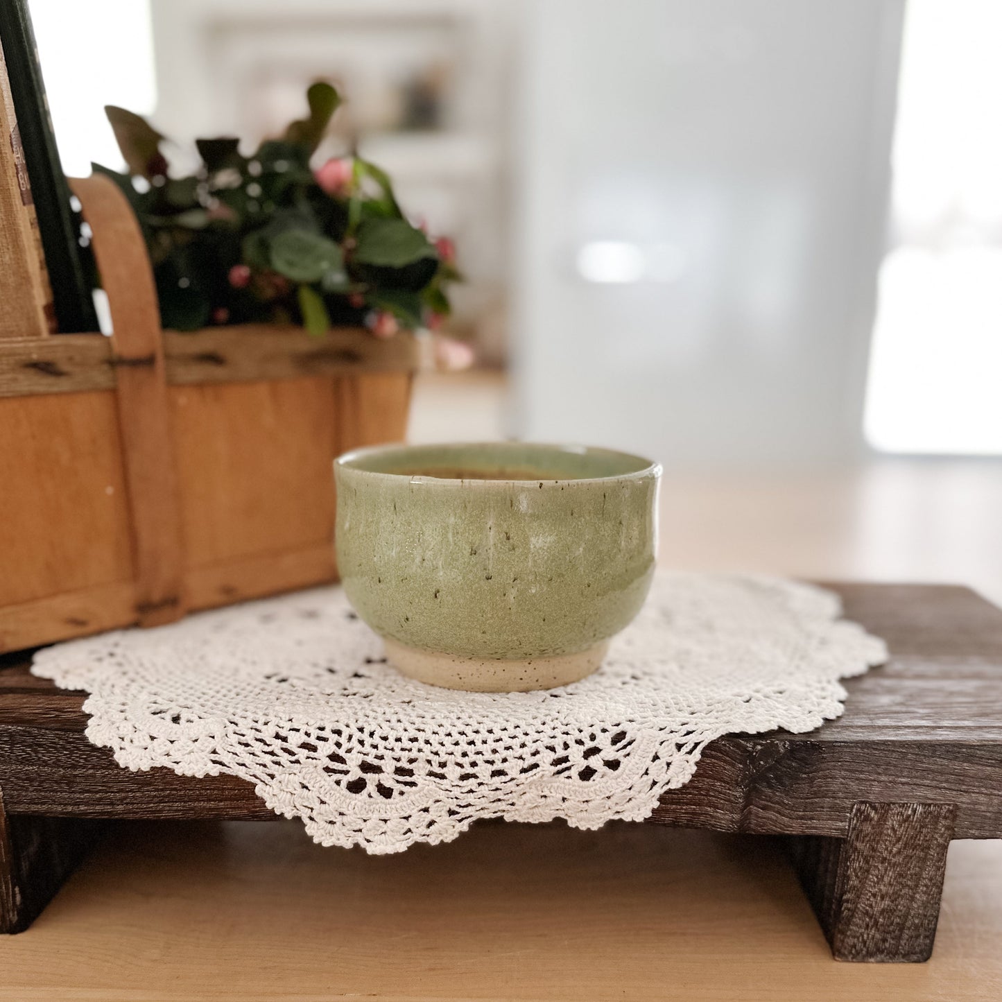Green ceramic bowl on a wooden surface with a doily underneath