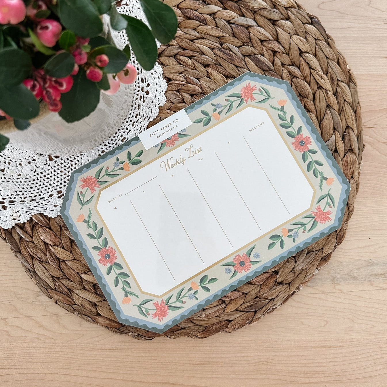 Decorative planner with floral design on a woven mat with a plant in the background